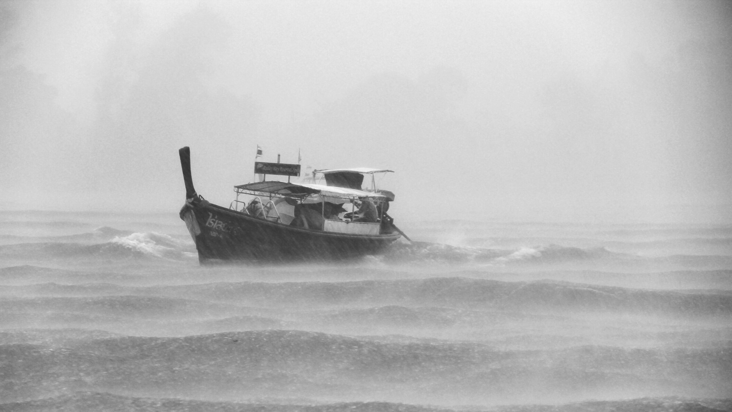 A storm approaching over a lake with waves crashing against boats