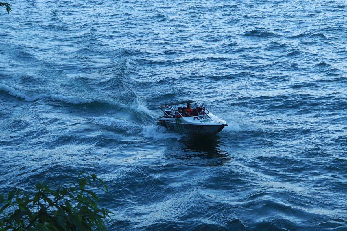 A smiling boater standing next to his insured pontoon boat after receiving approval for a minor repair claim.